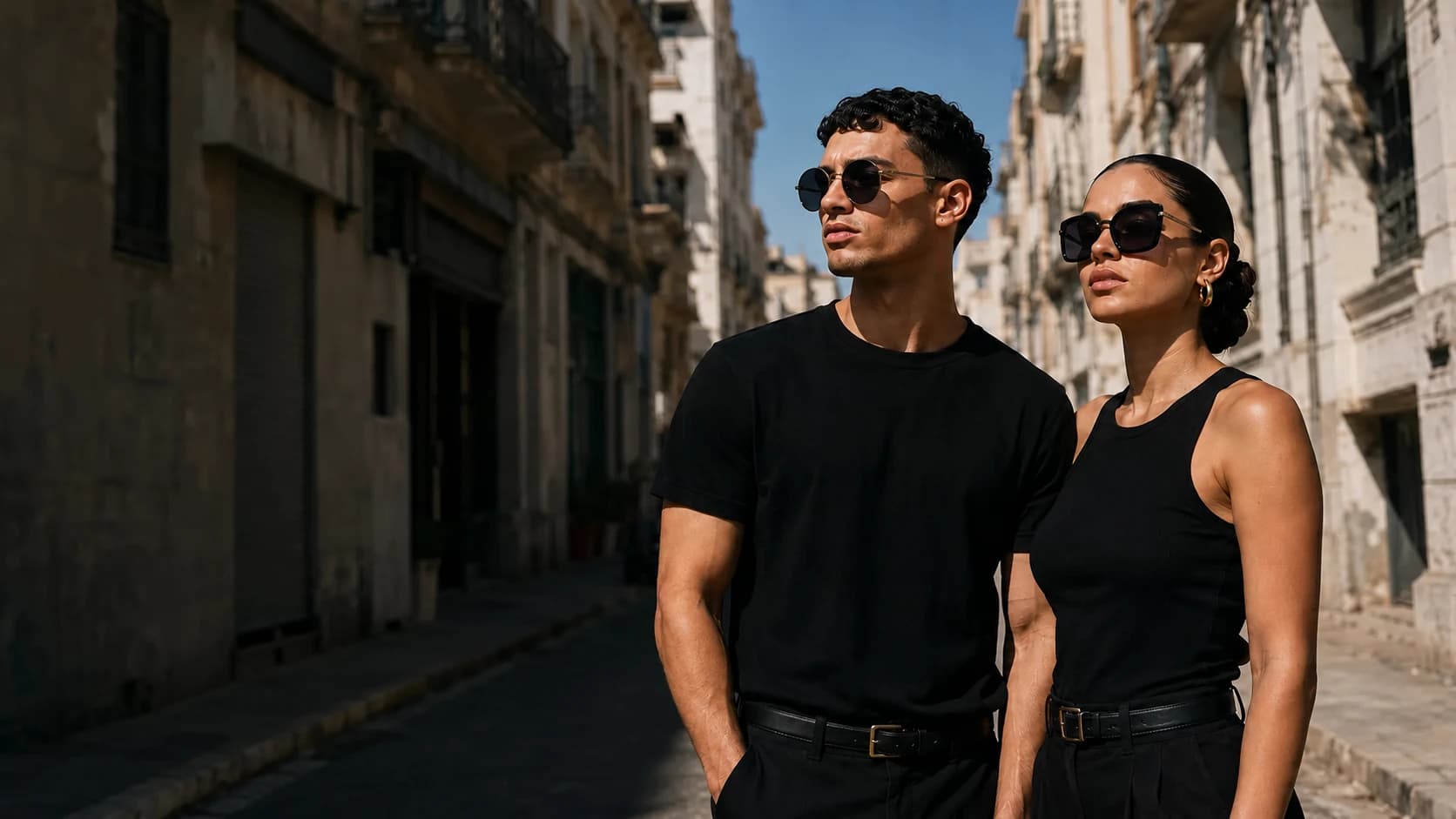 Two models wearing sunglasses on a sunlit Algerian city street